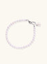 Delicate freshwater pearl bracelet with rhodium-plated silver clasp and single pearl drop charm on cream background