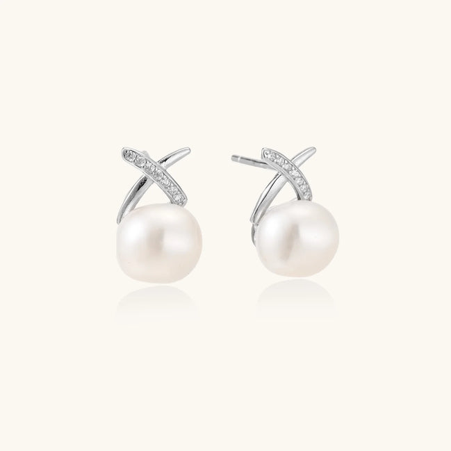 Rhodium-plated silver stud earrings with sparkling X design above lustrous round freshwater pearls on white background.