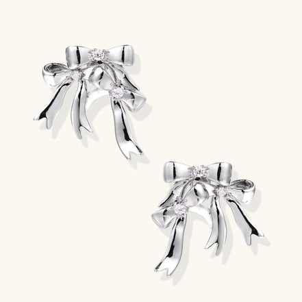 Sculptural bow earrings in polished white gold plate with sparkling zirconia stones and flowing ribbon details