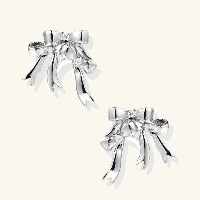 Sculptural bow earrings in polished white gold plate with sparkling zirconia stones and flowing ribbon details