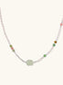 Delicate pearl necklace with pale green serpentine jade centerpiece and colorful agate beads on cream background