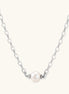 Dainty rhodium-plated silver chain necklace with centered 10mm freshwater pearl and crystal accents on cream background