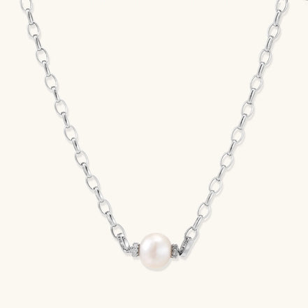 Dainty rhodium-plated silver chain necklace with centered 10mm freshwater pearl and crystal accents on cream background