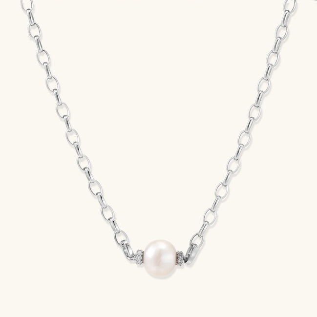 Dainty rhodium-plated silver chain necklace with centered 10mm freshwater pearl and crystal accents on cream background