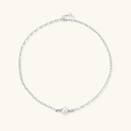 Dainty rhodium-plated silver chain necklace with centered 10mm freshwater pearl and crystal accents on cream background