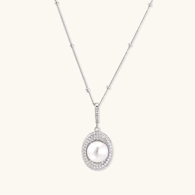 Oval sterling silver pendant with crystal halo surrounding a white freshwater pearl on delicate chain