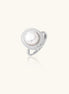 Silver ring with lustrous white pearl center surrounded by sparkling crystal halo on light background.